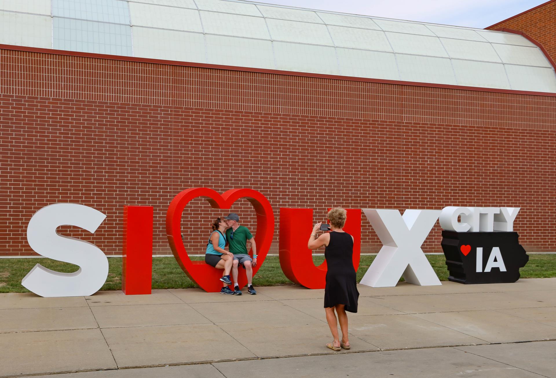 photo taken of couple sitting in heart of Sioux City sign