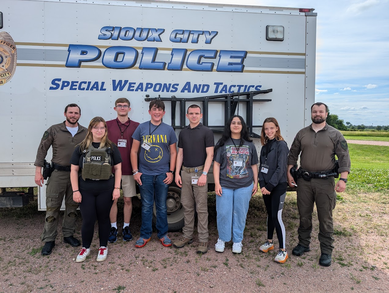 Students and instructors standing next to Sioux City Police vehicle